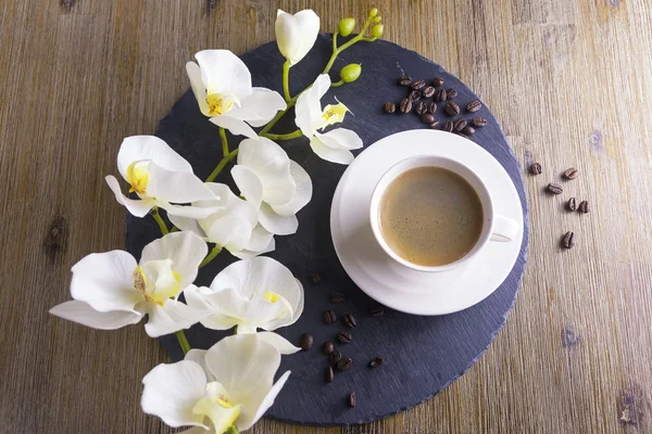 Kompozycja z filiżankę czarnej herbaty na tle czarno -brązowy. Kubek czarnej kawy z ziaren kawy i białych kwiatów. To simbolizes ładne rano smaczne herbaty. — Zdjęcie stockowe
