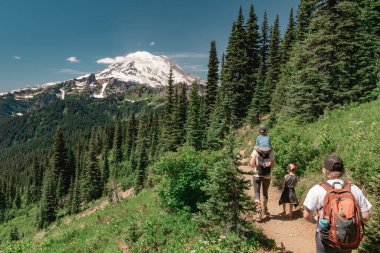 Çocuklarla birlikte Naches Tepesi Döngü Yolu 'nda Rainier Dağı' na doğru yürüyüşe çıkan genç kadınlar. Rainier Ulusal Parkı