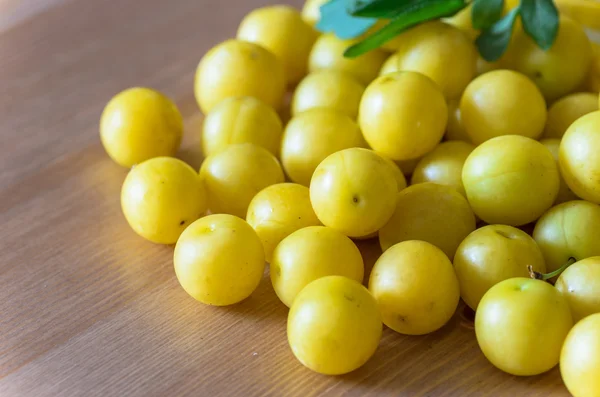 Hög med gula mirabelle plommon på träbord — Stockfoto