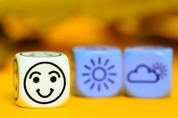 concept of autumn weather - emoticon and weather dice on orange 