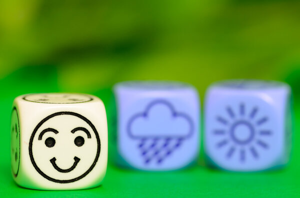 concept of summer weather - emoticon and weather dice on green b