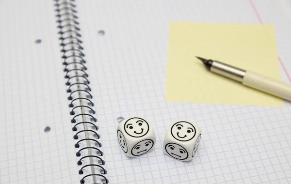 Open exercise book with mood dice (happy) and yellow sticky card — Stock Photo, Image