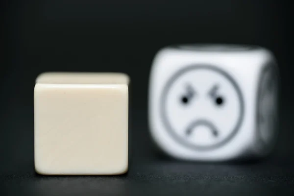 Blank dice with emoticon dice (sad) in background — Stock Photo, Image