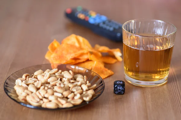 Ungesunde Snacks auf dem Tisch mit Totenkopfwürfeln und Fernbedienung — Stockfoto