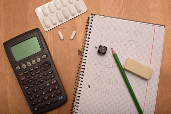 Studieplats med miniräknare och smärtstillande medel i bakgrunden — Stockfoto