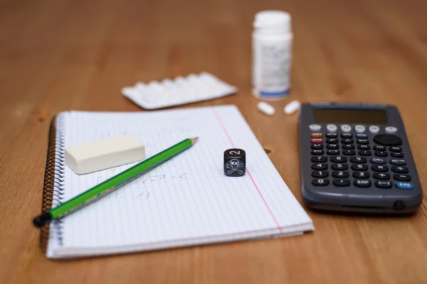 Lugar de estudio con calculadora y analgésicos en segundo plano — Foto de Stock