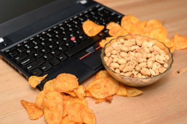 Açık laptop klavye ve yay üzerinde dağınık cips ile yakın