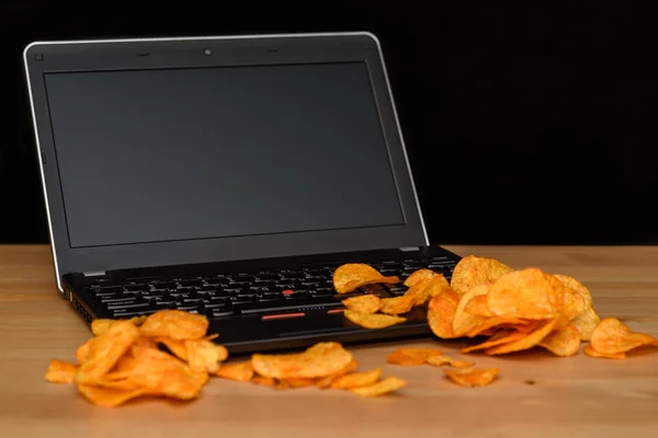 Open laptop with chips scattered on keyboard isolated on black b — Stock Photo, Image