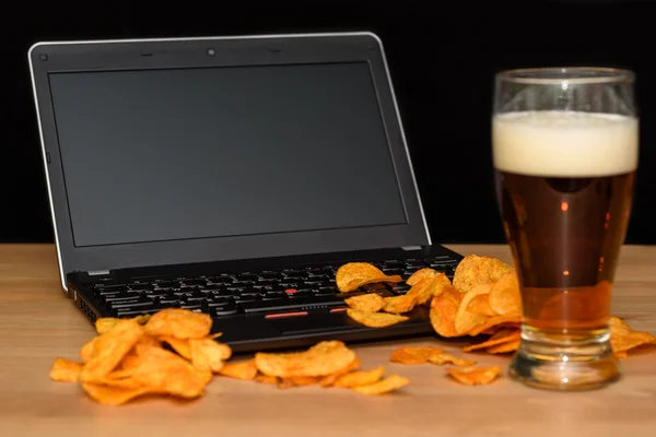 Open laptop with chips scattered on keyboard isolated on black b — Stock Photo, Image