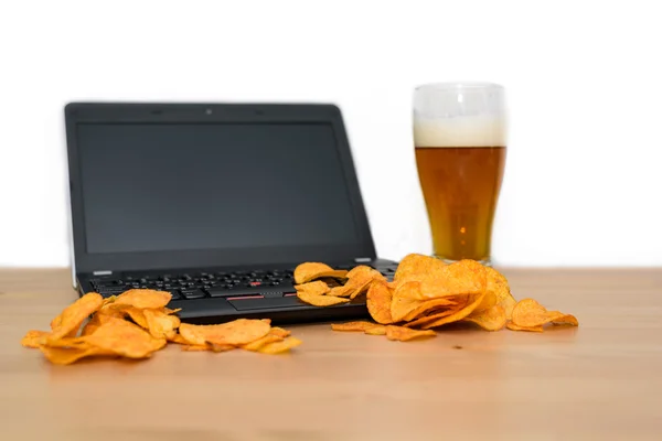 Öppna laptop med chips utspridda på tangentbordet isolerad på vita b Royaltyfria Stockbilder