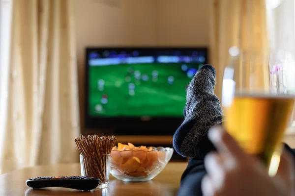 Fernsehen, Fernsehen (Fußballspiel) mit Füßen auf dem Tisch und — Stockfoto