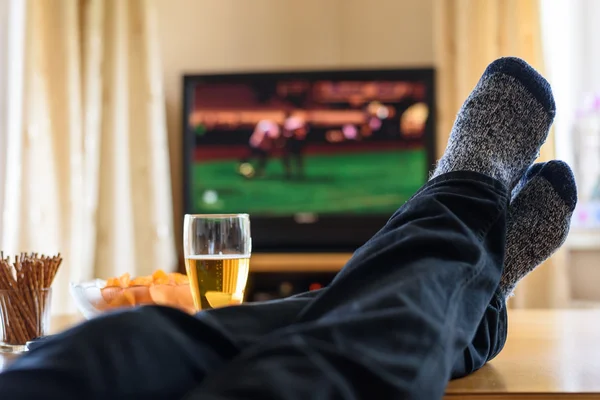 Fernsehen, Fernsehen (Fußballspiel) mit Füßen auf dem Tisch und — Stockfoto