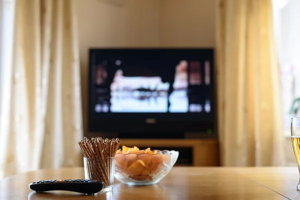 Televisão, TV assistindo (filme) com lanches deitados na mesa — Fotografia de Stock
