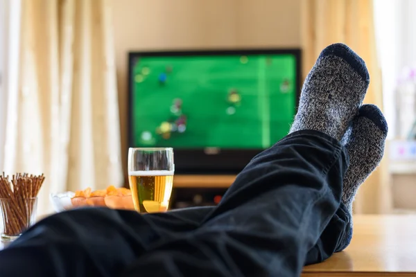 Fernsehen, Fernsehen (Fußballspiel) mit Füßen auf dem Tisch und — Stockfoto