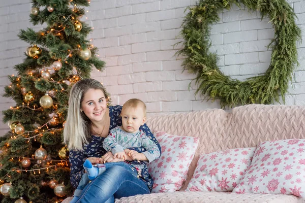 Una Hermosa Joven Sienta Sofá Con Niño Cerca Del Árbol — Foto de Stock