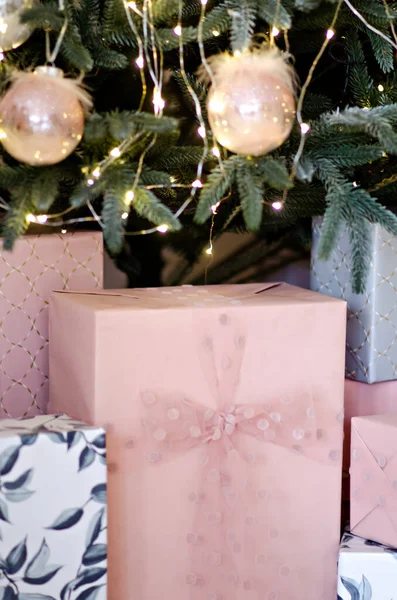 许多礼物用粉色和灰色的纸包裹着 用空气缎带和蝴蝶结装饰着 在圣诞树下挂着圣诞老人的花环 新年的奇迹 复制空间背景 — 图库照片