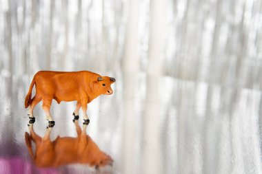 Kahverengi bir boğa öküzü parlak, bulanık, gümüşi bir arka plana karşı duruyor. Tatil kartı boş. Yılın Noel Sembolü. Yeni yıl posteri, takvim. Mesaj için yer. Uzayı kopyala, şablon. Süt ürünleri