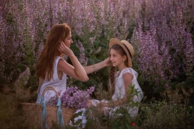 Beyaz elbiseli genç bir anne kızının saçlarını düzleştiriyor. Mor adaçayı tarlasının ortasında kafasına hasır bir şapka takıyor. Annelik bakımı. Hafta sonu kırsalda yürüyüş. Portreyi kapat