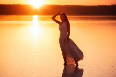 İnce, zarif, gün batımında saten tozlu elbisesi olan bir kız silueti. Genç bir kadın denizin, okyanusun üzerinde yürür. Saçlar rüzgarda uçuşuyor. Hafiflik, havalanma, ruhun özgürlüğü.