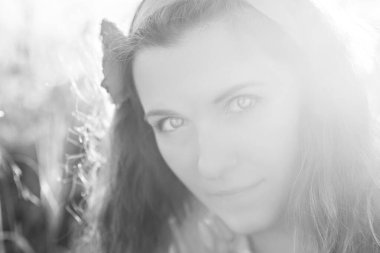 Ulusal kostüm giymiş kırmızı halkalı genç bir kadının yakın plan portresi haşhaş tarlasında işlenmiş bir gömlek. Kız dikenleri elinde tutuyor. Kırsalda yürü