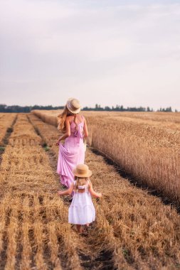 Kızı annenin elini tutar, gün batımında altın buğday tarlası boyunca yürür. Genç bir kadın ve pembe elbiseli bir kız ve hasır şapkalı bir kız çavdar ekmeğinin arasında, ayakları çamurun içinde duruyorlar. Kırsalda yürüyen bir zenci.