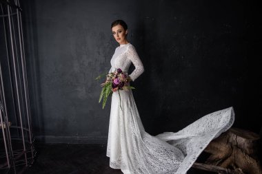 Duvağı olmayan beyaz bir elbise içinde moda gelini elinde bir buket tutuyor. Genç bir kadın siyah desenli arka planda büyük bir demir kuş kafesinin yanında duruyor. Hayali bir evlilik. Boşluğu kopyala