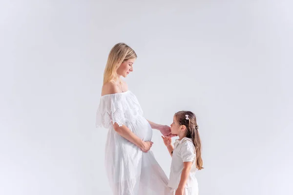 Niña Besa Abrazos Madre Embarazada Sobre Fondo Blanco Aislado Hermana — Foto de Stock