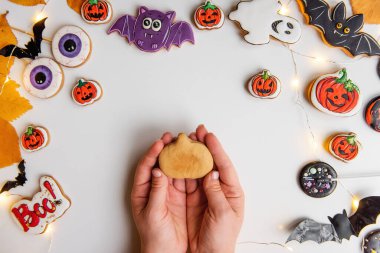 Turuncu kabak şeklinde zencefilli kurabiyenin kremayla nasıl çizileceği konusunda adım adım talimatlar. Birinci adım, elinde zencefil hamuru şeklinde bir balkabağı yatıyor. Beyaz izole arka planda Cadılar Bayramı tatlıları