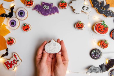 Turuncu kabak şeklinde zencefilli kurabiyenin kremayla nasıl çizileceği konusunda adım adım talimatlar. Üçüncü adım, beyaz üste, balkabağı tezgahını kalemle çiz. Soyutlanmış bir arka planda Cadılar Bayramı tatlıları