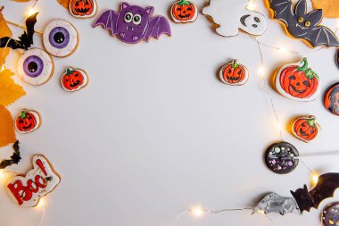 Beyaz izole arka planda Cadılar Bayramı zencefilli kurabiye çerçevesi, sarı, sonbahar yapraklı, çelenkli. Kutlama kartpostalı. Partideki çocuklar için tatlı yiyecekler ve tatlılar. Uzayı kopyala, taklit et