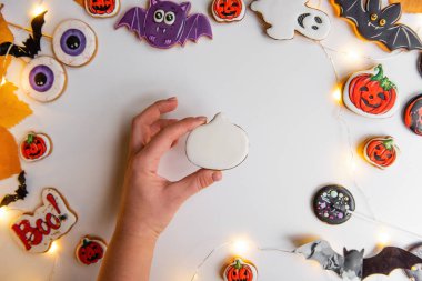 Turuncu kabak şeklindeki zencefilli kurabiyenin kremayla nasıl çizileceği konusunda adım adım talimatlar. Adım 2, balkabağı şeklini beyaz kremayla kapla. Soyutlanmış arka planda Cadılar Bayramı tatlıları