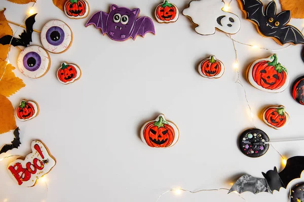 Beyaz izole arka planda Cadılar Bayramı zencefilli kurabiye çerçevesi, sarı, sonbahar yapraklı, çelenkli. Kutlama kartpostalı. Partideki çocuklar için tatlı yiyecekler ve tatlılar. Uzayı kopyala, taklit et