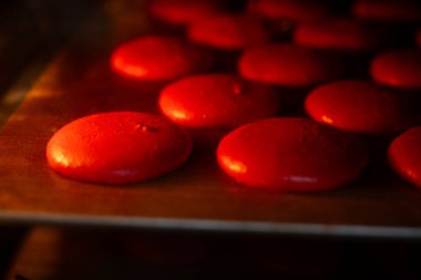 Sıcak bir fırının içinde tepside pişen kırmızı Makaronlar, şekerlemenin yavaşça yükseldiğini ve sıcaklıkta karakteristik ayaklarını geliştirdiğini ve lezzetli bir gurme tatlısı yarattığını gösteriyor.