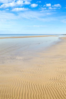 Dzintari Sahili, Jurmala, Letonya. Güneşli bir gün. Kumsalda dalgalı kum, bulutlu deniz ve mavi gökyüzü.