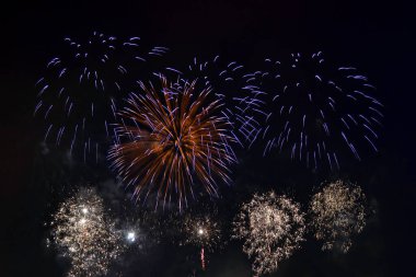 Gece gökyüzü arka planında çok renkli havai fişekler. Sarı ve mavi ışıklarla selamla. Ve alttan beyaz. tatil ve eğlence konsepti