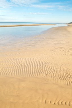 Kumsalda dalgalı kum, bulutlu deniz ve mavi gökyüzü. Dzintari Sahili, Jurmala, Letonya 'da güneşli bir gün.