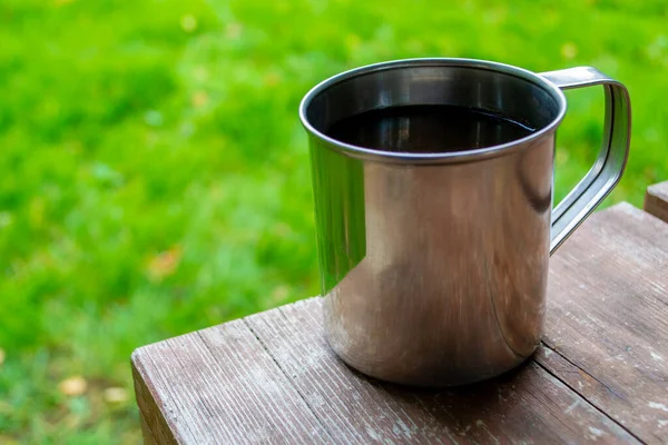 Kamp yaparken seyahat fincanının yakın çekimi. Çay ya da ahşap masada kahve olan metal bardak. Boşluğu kopyala.