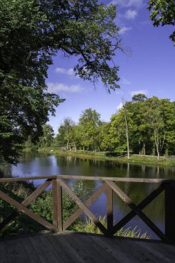 Jaunpils Gölü kıyılarındaki ahşap verandada park yeri ve çevresi güzel manzaralı. Açık güneşli gün.