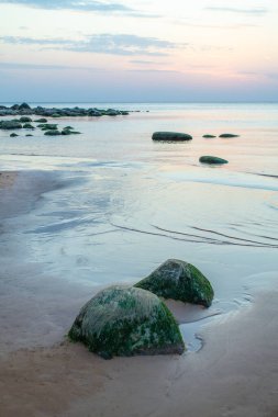 Letonya 'daki Vidzeme' nin taş kıyı şeridi. Gün batımında Riga körfezinin Rocky plajı. Güzel gökyüzü ve manzara.