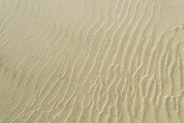 Sandstruktur an einer Meeresküste. Welliger Sand Hintergrund Nahaufnahme. — Stockfoto