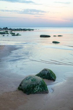 Letonya 'daki Vidzeme' nin taş kıyı şeridi. Gün batımında Riga körfezinin Rocky plajı. Güzel gökyüzü ve manzara.