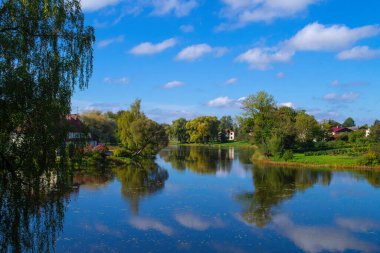 Güzel bir göl manzarası ve sahilde küçük evler. Açık güneşli bir günde Jaunpils Gölü.