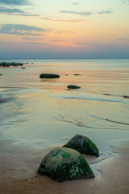 Gün batımında Riga körfezinin Rocky plajı. Letonya 'daki Vidzeme' nin taş kıyı şeridi. Güzel gökyüzü ve manzara.