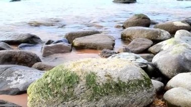 Kaya sahili. Sahildeki büyük ve küçük kayalar. Dalgalar denizde yuvarlanır.