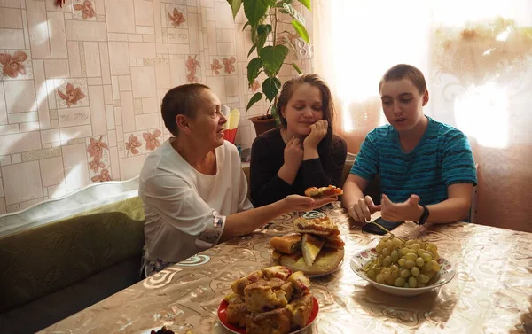 Los huéspedes están hablando en una mesa cubierta de pasteles caseros. Las personas mayores hablan con los jóvenes, ofrecen pasteles. — Foto de Stock