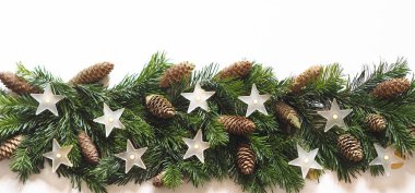 Ekran koruyucu ya da tebrik kartı. Çizgili doğal ladin dalları, köknar kozalakları ve beyaz mat yıldızlarının lambalarıyla beyaz ahşap zemin..