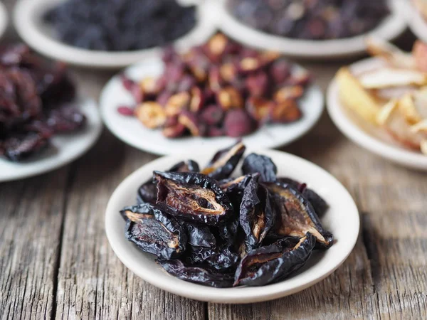 Dried plum on the foreground.Background with bowls with various dried fruits on a wooden ancient background. Home preparation of dried fruits.