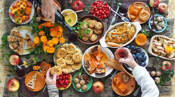 Style champêtre. Table de Thanksgiving. Beaucoup de nourriture avec du vin rouge. Les invités mangent de la nourriture avec leurs mains sur la table. Vue d'en haut. — Photo