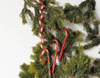 Kartlar için tebrik ederim, mesajlar için de tebrikler. Beyaz zemin üzerinde ladin dalları ve karamel lolipoplar arkaplan ve metin için bir boşluk olarak.