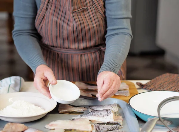 Hand of an elderly woman salting fish on a cutting kitchen board. Process of cutting pike fish for frying in a pan. — Stock Image Hand Elderly Woman Salting Fish Cutting Kitchen Board Process Cutting Royalty Free Stock Images